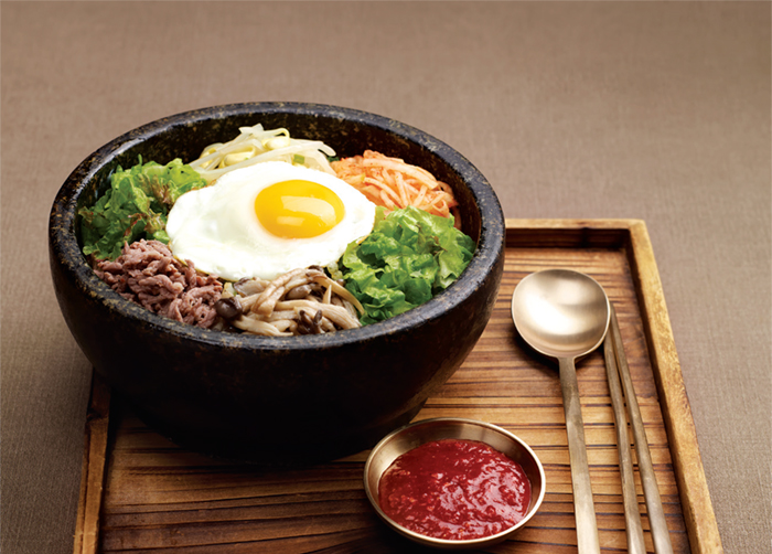 Bibimbap. Cooked rice served with fresh and seasoned vegetables, minced raw beef and chili paste.