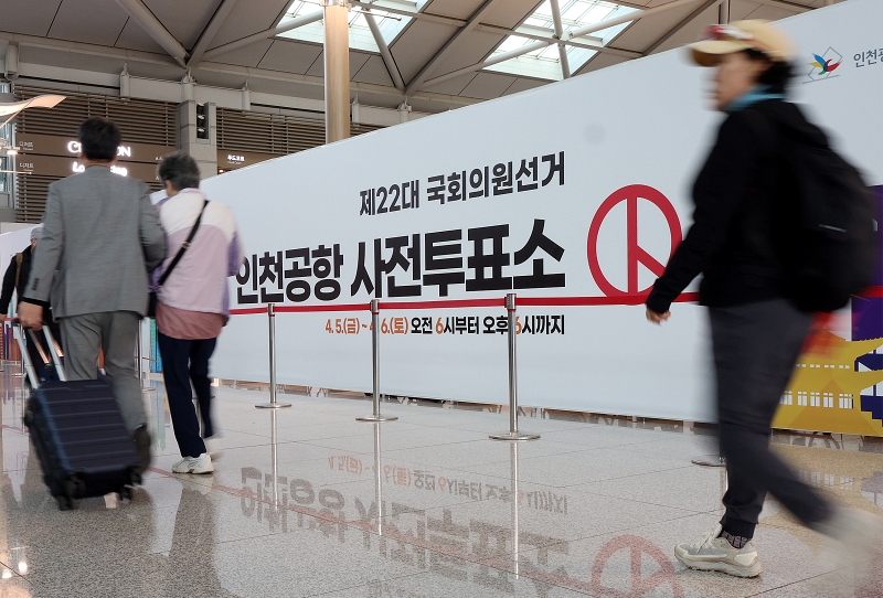  Des voyageurs passent devant un bureau de vote installé dans le terminal 1 de l'aéroport d'Incheon, le 5 avril 2024.