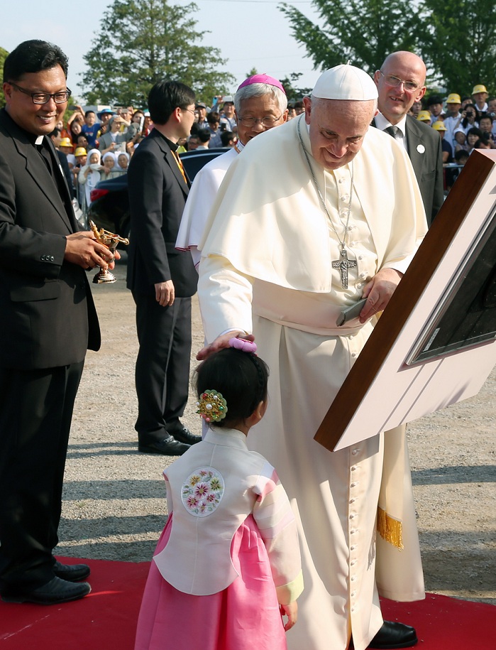 프란치스코 교황이 솔뫼성지를 찾아 방명록에 서명후 어린이의 머리를 쓰다듬으며 복을 내리고 있다. 