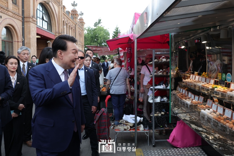 Yoon Suk Yeol salue les commercants du plus ancien marché de la capitale polonaise, Hala Mirowska, le 14 juillet 2023.