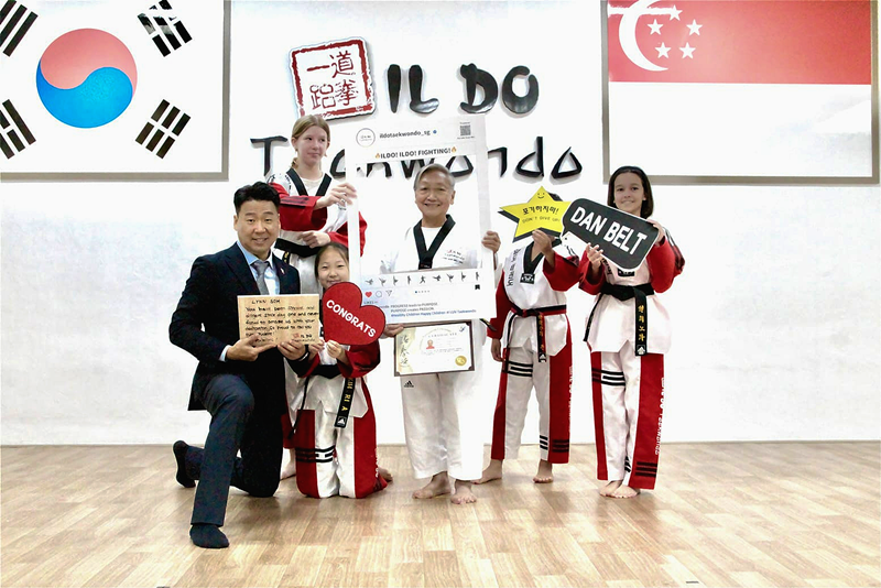 Lynn Soh (au centre), une des élèves de Kim Jong Yoon (à gauche) pose avec son professeur et d’autres élèves après avoir reçu la ceinture noire 2e dan au club Ildo Academy du quartier de Bukit Timah, à Singapour, en février dernier. 
