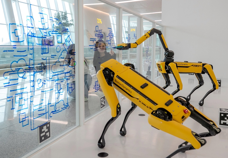 Deux voyageuses regardent des robots dessinant sur une vitre du terminal 2 de l’aéroport d’Incheon, le 16 décembre 2024. Cette exposition spéciale de robots quadrupèdes se déroulera pendant six mois de 8h à 20h. © Agence de presse Yonhap