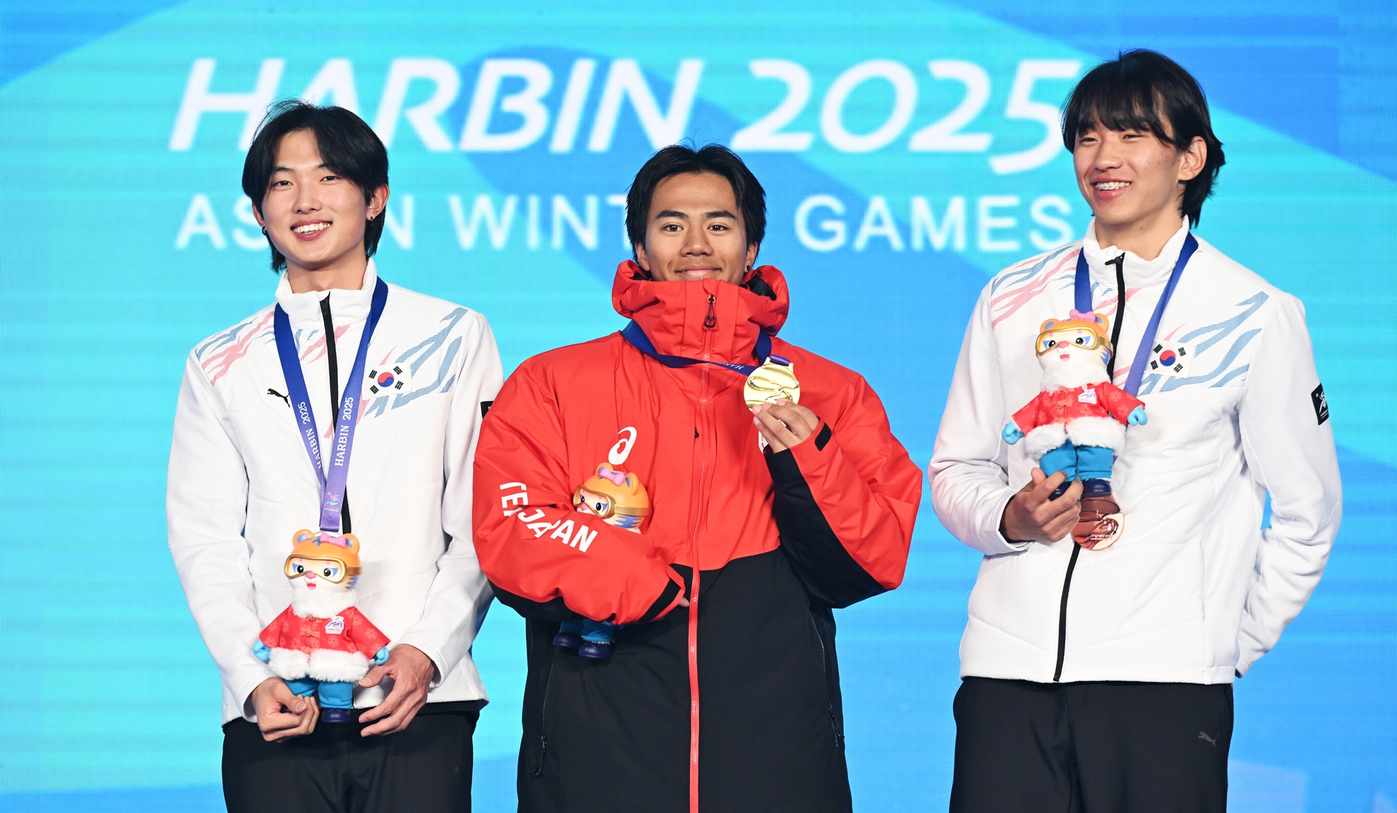 Yoon Jonghyun (à gauche) et Shin Yeongseop (à droite) posent avec le Japonais Rai Kasamura sur le podium du ski freestyle big air masculin des Jeux asiatiques d’hiver de Harbin, au Freeski Big Air Stadium, le 12 février 2025. © Agence de presse Yonhap