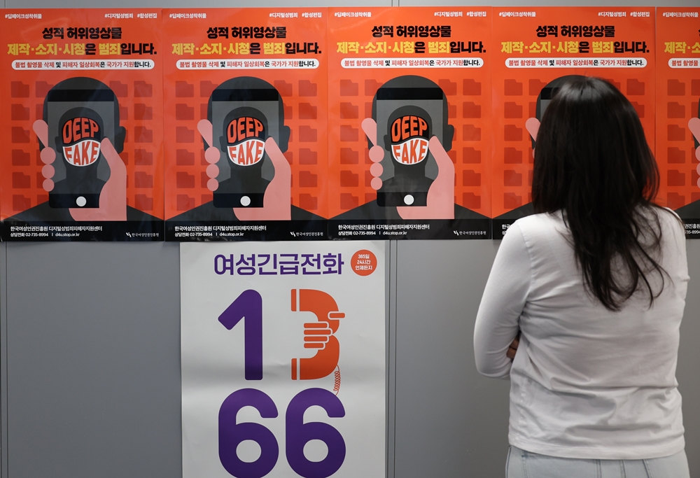 Une femme regarde les affiches de prévention contre les deepfakes pornographiques. © Agence de presse Yonhap
