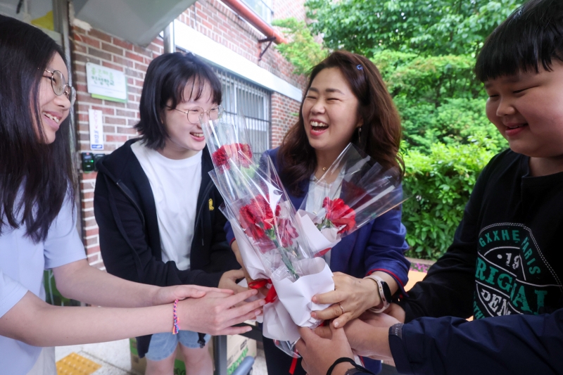 Des élèves de l’école élémentaire Dongil, dans l’arrondissement de Nowon, à Séoul, offrent des œillets à leur enseignante à l’occasion de la fête des professeurs, le 15 mai 2025. © Agence de presse Yonhap