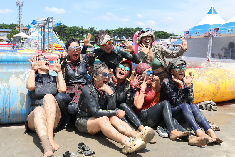 Un groupe de festivaliers posent au bord d’une piscine de boue à Boryeong, le 26 juillet 2025. © Lee Jeong Woo / Korea.net