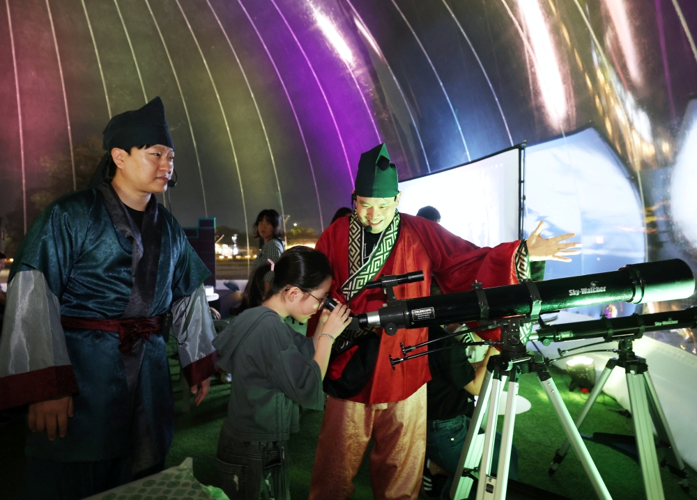 Une participante &agrave; l&rsquo;activit&eacute; &laquo; Ah, the night of Silla &raquo; regarde dans un t&eacute;l&eacute;scope pr&egrave;s de l&rsquo;observatoire de Cheomseongdae &agrave; Gyeongju, le 16 septembre 2025. &copy; Park Daejin / Korea.net