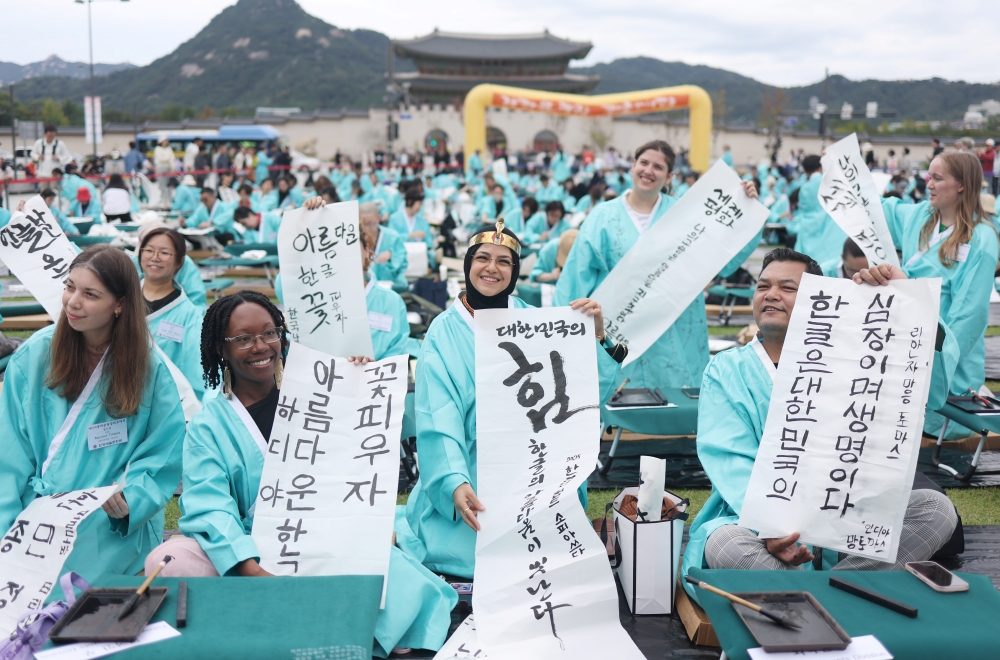 Des participants à un concours de calligraphie organisé à l’occasion du 579e anniversaire de la création de l'alphabet coréen, le hangeul, posent avec leurs créations sur la place Gwanghwamun, à Séoul, le 9 octobre 2025. © Agence de presse Yonhap