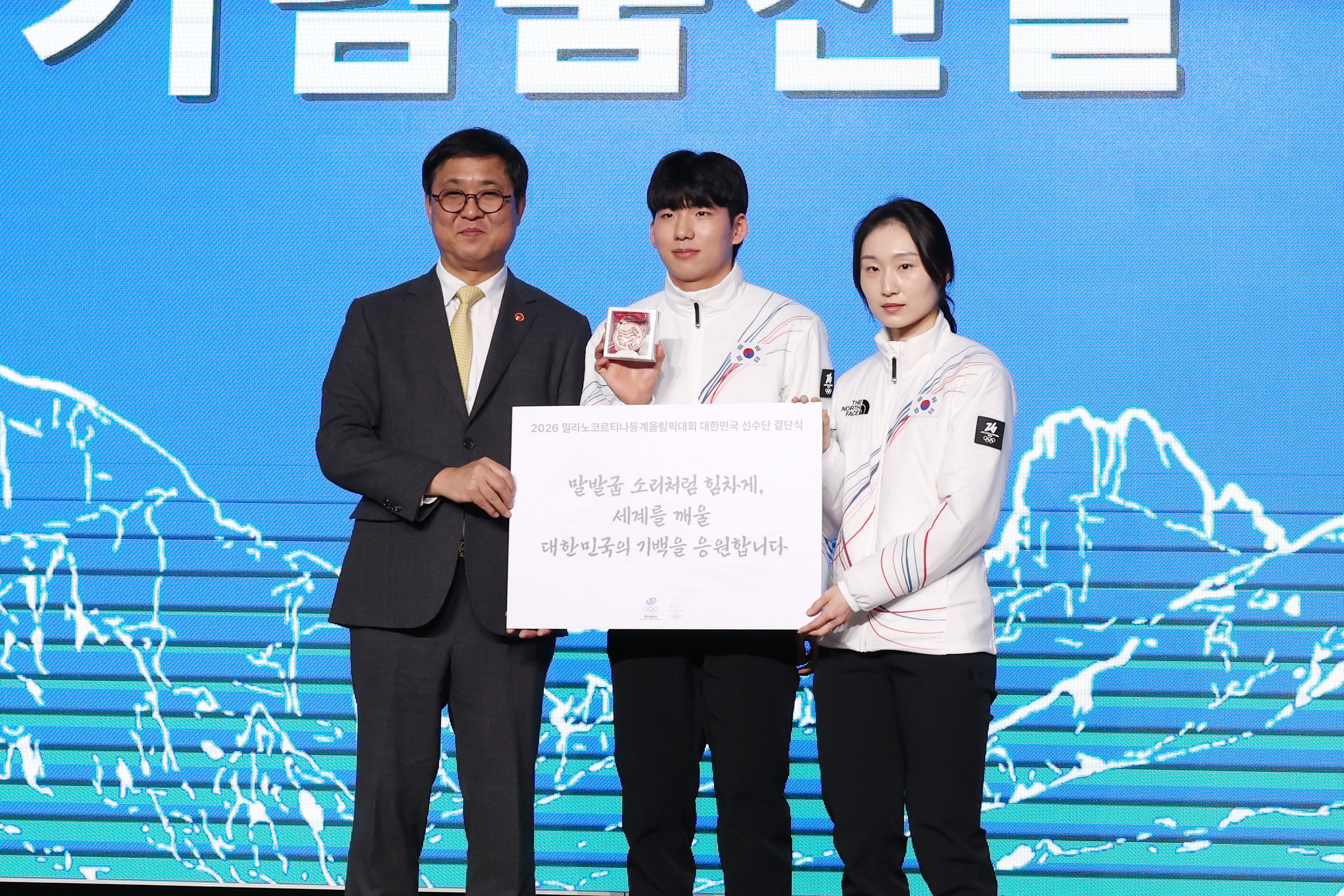 Le ministre de la Culture, des Sports et du Tourisme, Chae Hwi-young, pose avec les patineurs de vitesse Chung Jae-won et Choi Min-jeong, lors de la cérémonie d’encouragement organisée au parc olympique de Séoul, le 22 janvier 2026. © Lee Jeong Woo / Korea.net