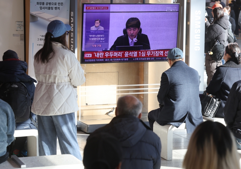 Un groupe de personnes regarde la diffusion en direct du proc&egrave;s de l&rsquo;ex-pr&eacute;sident Yoon Suk Yeol sur une t&eacute;l&eacute;vision de la gare de S&eacute;oul, le 19 f&eacute;vrier 2026. &copy; Agence de presse Yonhap