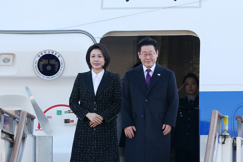 Le président Lee Jae Myung (à droite) et son épouse Kim Hea Kyung sur le tarmac de l’aéroport de Séoul, à Seongnam, le 13 janvier 2026. © Lee Jeong Woo / Korea.net 