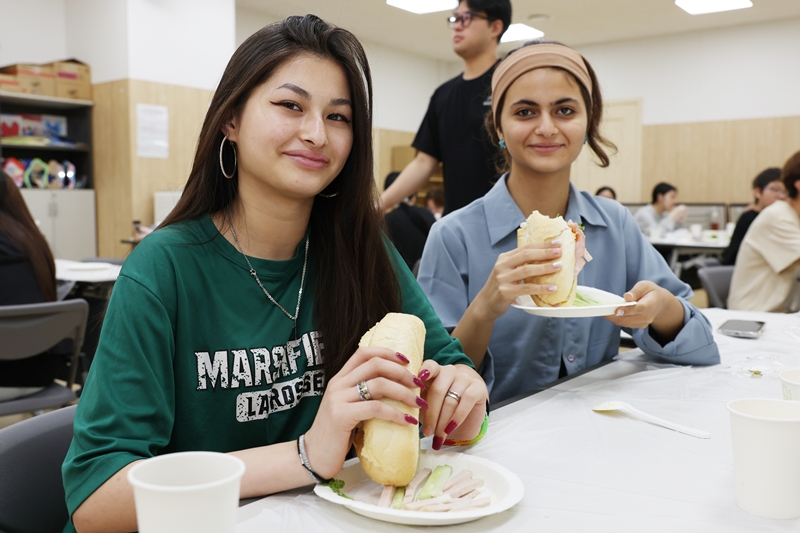 Deux jeunes filles posent avec un banh mi, un sandwich vietnamien, lors d’un atelier de cuisine organisé au Seoul Global Youth Education Center, dans l’arrondissement de Yeongdeungpo, le 11 septembre 2025. © Lee Jeong Woo / Korea.net