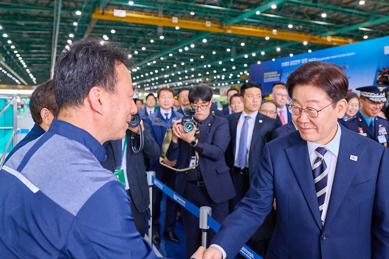 Le pr&eacute;sident Lee Jae Myung serre la main d&rsquo;un ouvrier de la soci&eacute;t&eacute; Korea Aeroscpace Industries, &agrave; Sacheon, dans le Gyeongsang du Sud (Gyeongsangnam-do), le 25 mars 2026. &copy; Cheong Wa Dae