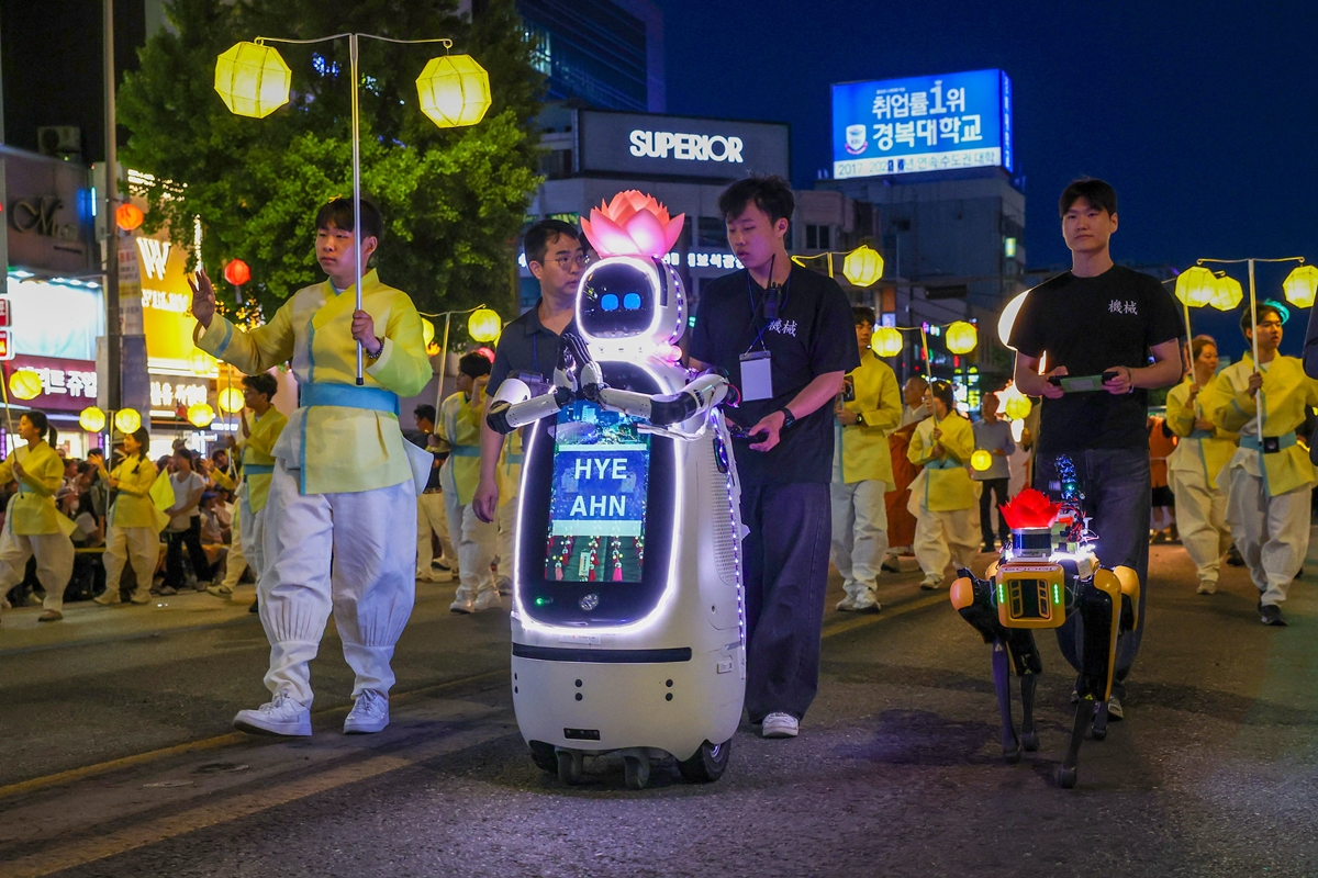Le moine robot Hyeahn d&eacute;ambule dans les rues de S&eacute;oul lors d&rsquo;un d&eacute;fil&eacute; de l&rsquo;universit&eacute; Dongguk, organis&eacute; pour la f&ecirc;te des lanternes, dans le centre de S&eacute;oul, le 16 mai 2026. &Agrave; ses c&ocirc;t&eacute;s marchent Googi, un robot quadrup&egrave;de charg&eacute; de la s&eacute;curit&eacute; de la parade. &copy; Lee Jeong Woo / Korea.net