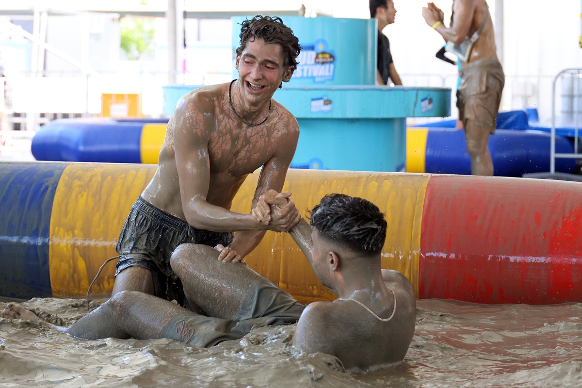 Deux jeunes hommes s’amusent dans une piscine de boue le 24 juillet 2026. © Agence de presse Yonhap