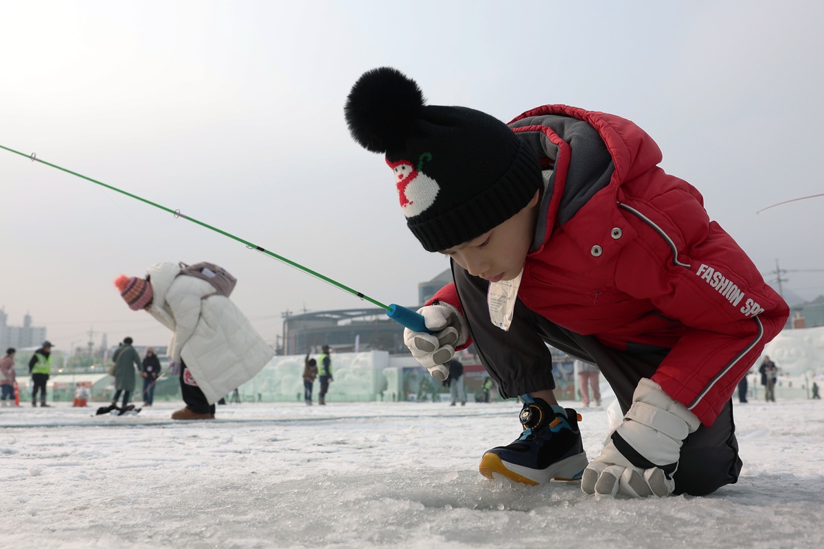 Un enfant pêche la truite sur la glace du Hwacheon Sancheoneo Ice Festival 2025. © Korea.net DB