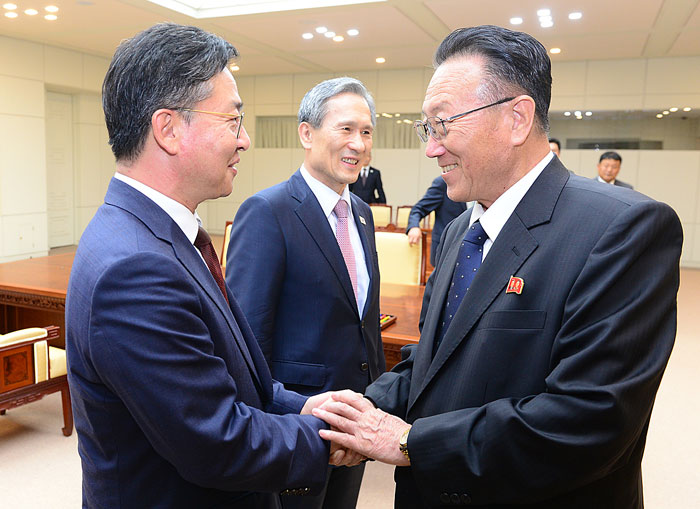 25일 새벽 판문점 평화의 집에서 한국측 대표인 홍용표 통일부 장관(왼쪽)과 북측 대표 김양건 노동당 대남비서(오른쪽)가 김관진 국가안보실장(가운데)이 지켜보는 가운데 악수하고 있다.