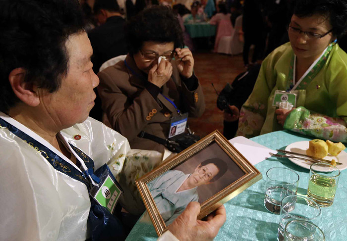 20일 이산가족 상봉행사에서 김용자(68)씨(왼쪽)가 동생 김영실씨에게 어머니 서정숙씨의 사진을 보여주며 눈물짓고 있다. 서정숙씨는 상봉을 며칠 앞두고 숨을 거뒀다. (사진: 연합뉴스)