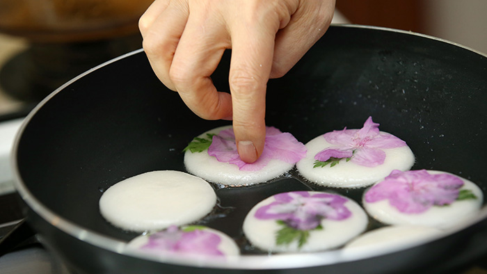 Placez les pétales d'azalées sur le côté cuit. Assurez-vous de maintenir une cuisson à feu doux pour que la surface des gâteaux de riz soit bien homogène et plate.