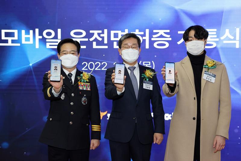 Le ministre de l'Intérieur et de la Sécurité Jeon Hae-cheol (au centre), le chef de l'Agence nationale de la police coréenne (KNPA) Kim Chang Yong (à gauche), et le futur étudiant Bang Jin-sol montrent leur permis de conduire mobile durant une cérémonie tenue sur un site d'examen du permis de conduire à Sangam, dans le district de Mapo, à Séoul, le 27 janvier 2022.
