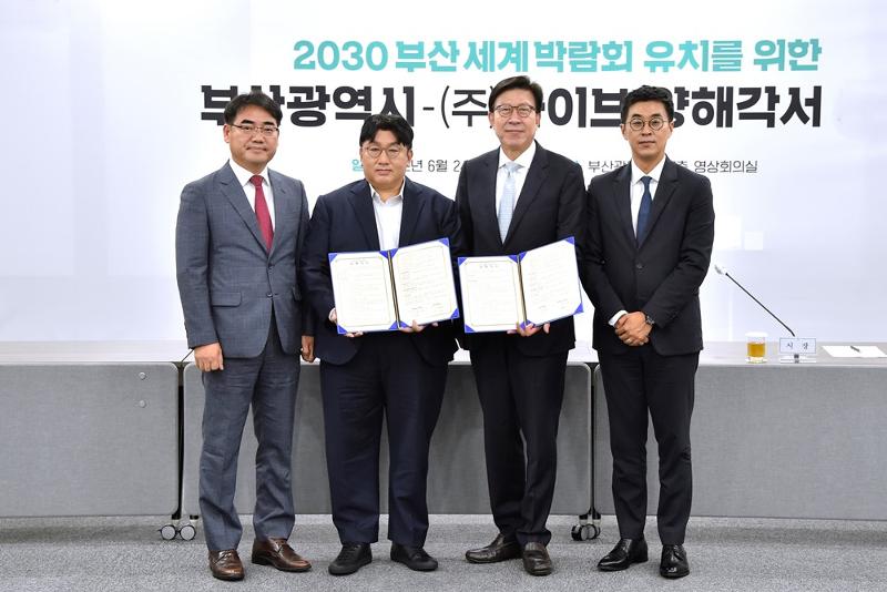Le maire de Busan, Park Heong-joon (troisième à gauche), et le président de Hybe, Bang Si-hyuk (deuxième à gauche), posent pour une photo après avoir signé un protocole d'accord sur la candidature de la ville à l'exposition universelle de 2030. De gauche à droite : Lee Seong-kweun, vice-maire chargé des affaires économiques, Bang, le maire Park et le PDG de Hybe, Park Ji-won. ⓒ Municipalité de Busan 