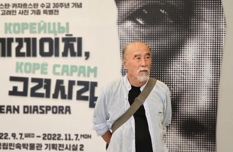 Viktor An, photographe ouzbek coréen, pose devant l'affiche promotionnelle de son exposition « Diaspora coréenne » au Musée national folklorique de Corée, dans le district de Jongno à Séoul. © Media Saram
