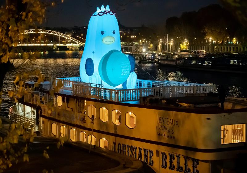 Un bateau de croisière installé avec Boogi, la mascotte de la ville métropolitaine de Busan sur le thème de la mouette, se trouve sur la Seine, à Paris, le 29 novembre, lors de la 171e assemblée générale du Bureau international des expositions (BIE). Sur la photo, le Boogi de 8 m de haut tient un macaron avec des lunettes sur la tête.