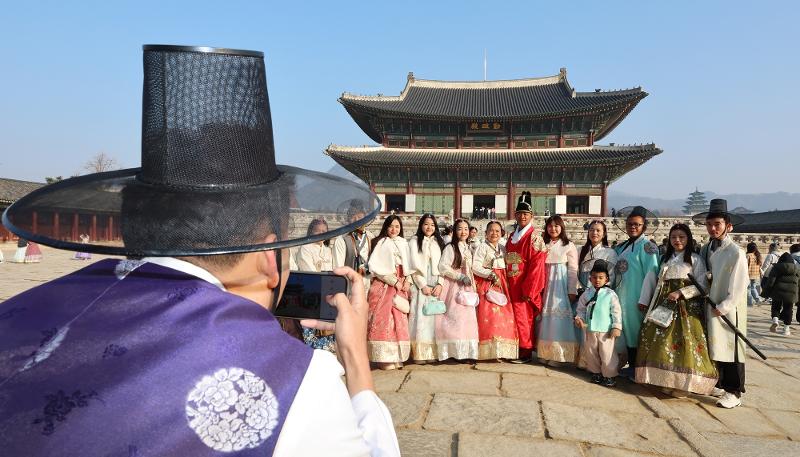 Des touristes étrangers vêtus d’un hanbok posent devant une des portes du palais Gyeongbok, à Séoul, le 12 février 2024. © Agence de presse Yonhap