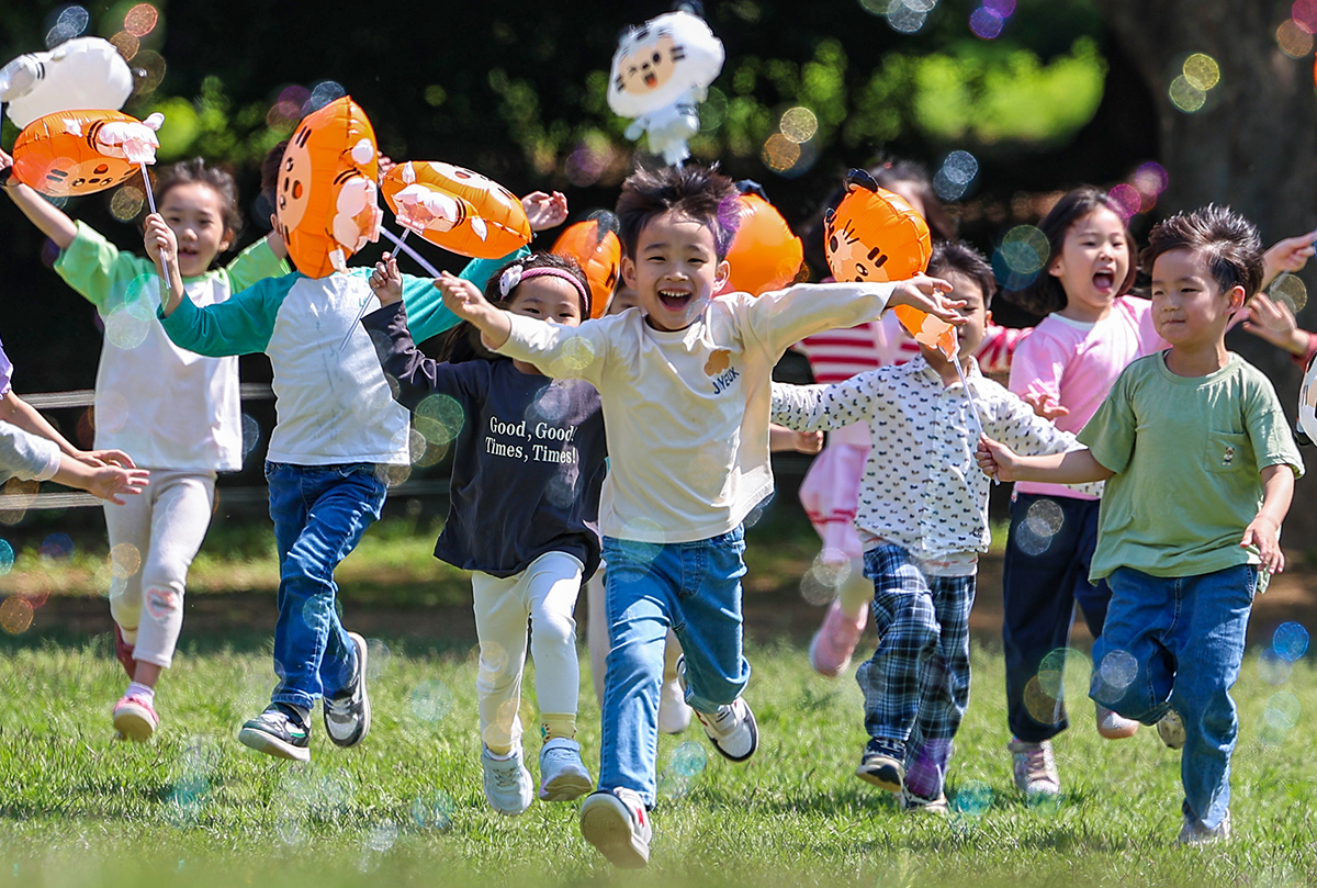 Des enfants jouent avec des bulles de savon devant le musée Baekje de Séoul, au parc olympique de Songpa, le 2 mai 2024.