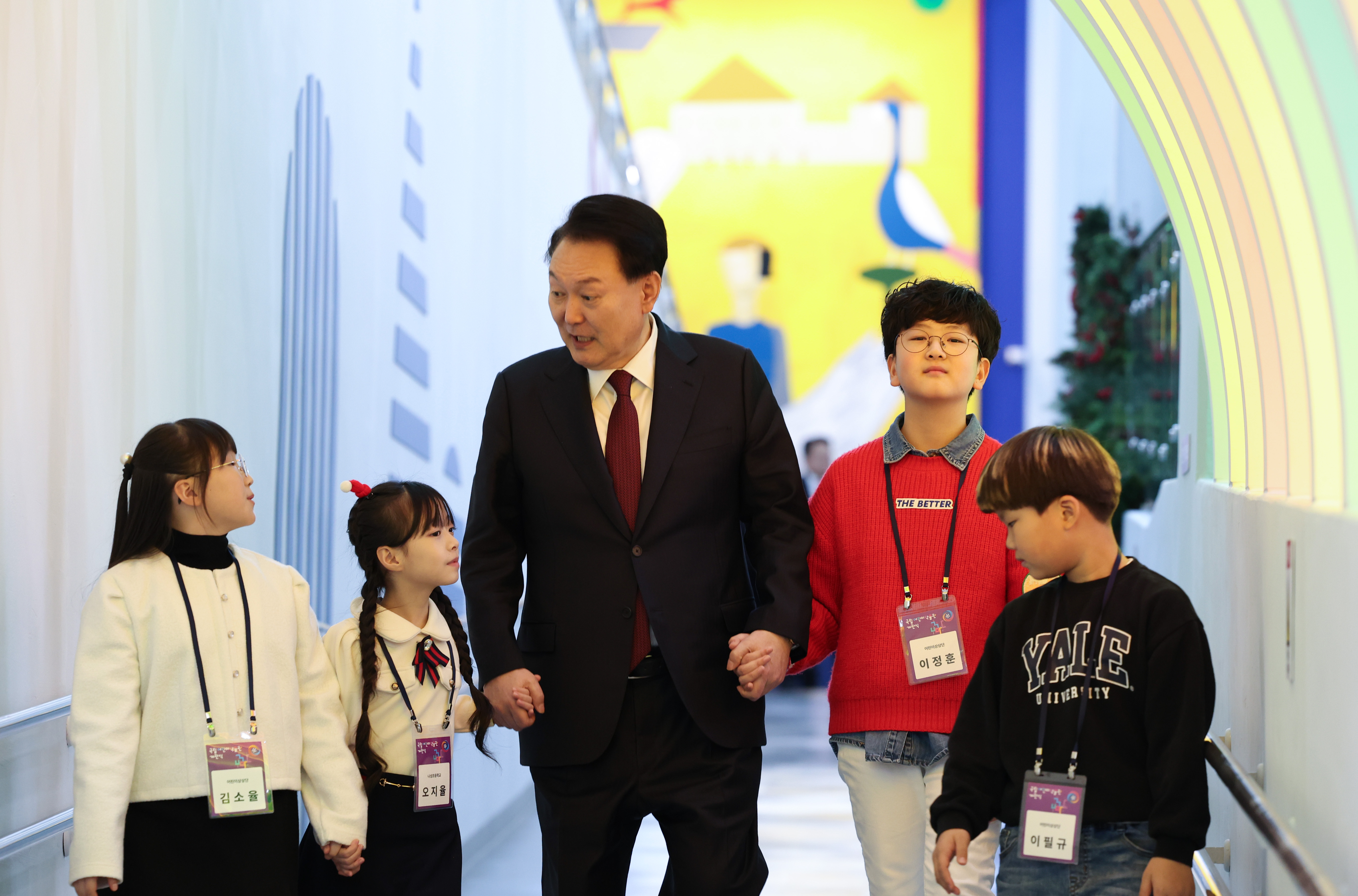Le président Yoon Suk Yeol marche avec des enfants lors de la cérémonie d’ouverture du musée national des enfants, à Sejong, le 26 décembre 2023. Le gouvernement a supprimé les critères de revenu nécessaires à l’attribution des subventions pour les traitements de fertilité et a augmenté la somme allouée aux familles de 700 000 à un million de won par enfant. 