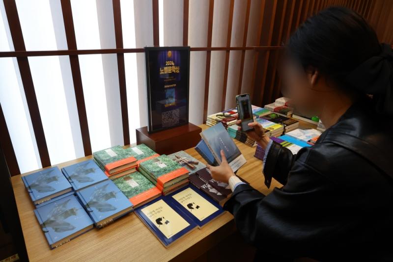 Des lecteurs prennent en photo l'espace spécialement dédié à la nouvelle lauréate du prix Nobel de littérature, Han Kang, dans la librairie Kyobo, dans le centre de Séoul, le 10 octobre 2024. © Agence de presse Yonhap