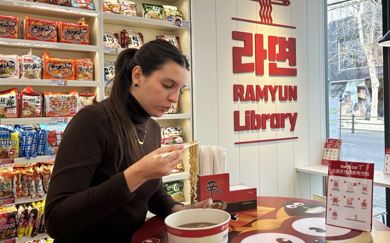 Une touriste déguste des nouilles instantanées à la bibliothèque ramyeon du quartier d’Hongdae, à Séoul, le 18 mars 2024. © Hong Angie / Korea.net