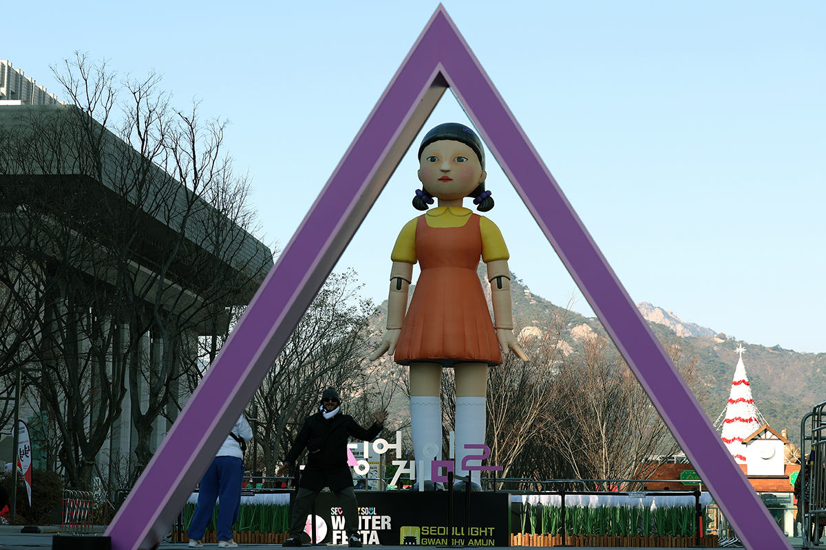 Un touriste pose devant une poupée gonflable de Young-hee, le robot emblématique de la série Netflix Squid Game sur la place Gwanghwamun, le 18 décembre 2024.