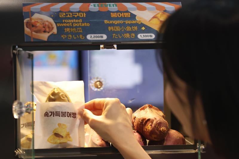 Une cliente achète un bungeoppang, un gâteau en forme de poisson, dans une supérette à Séoul, ce 11 décembre 2024. © Agence de presse Yonhap