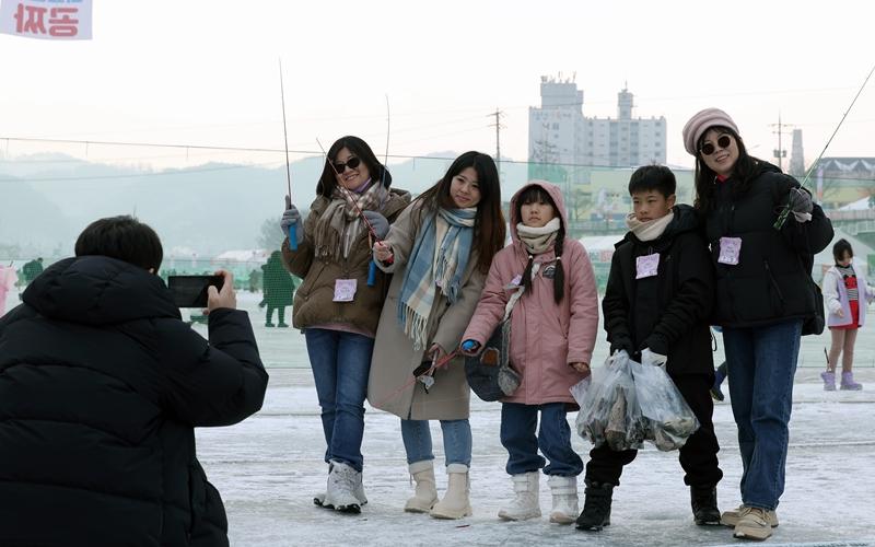 Un groupe d’apprentis pêcheurs à la truite posent sur la glace du festival, le 14 janvier 2025. © Lee Jun Young / Korea.net