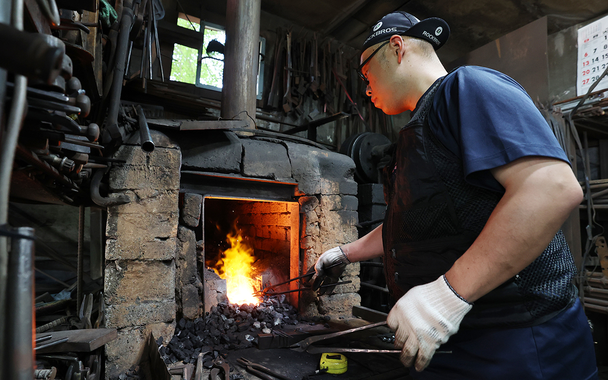 Un forgeron de la Brothers' Blacksmith Workshop travaille un morceau de fer dans son atelier situé à Séoul, le 10 juillet 2025.