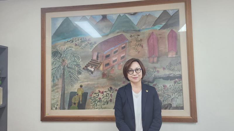 Lee Na-young, présidente du Korean Council for Justice and Remembrance for the Issues of Military Sexual Slavery by Japan, pose devant un tableau signé Kang Duk-kyung, une victime de l’esclavage sexuel perpétré par l’armée japonaise, à Séoul, le 24 juillet 2025. © Lee Jihae / Korea.net