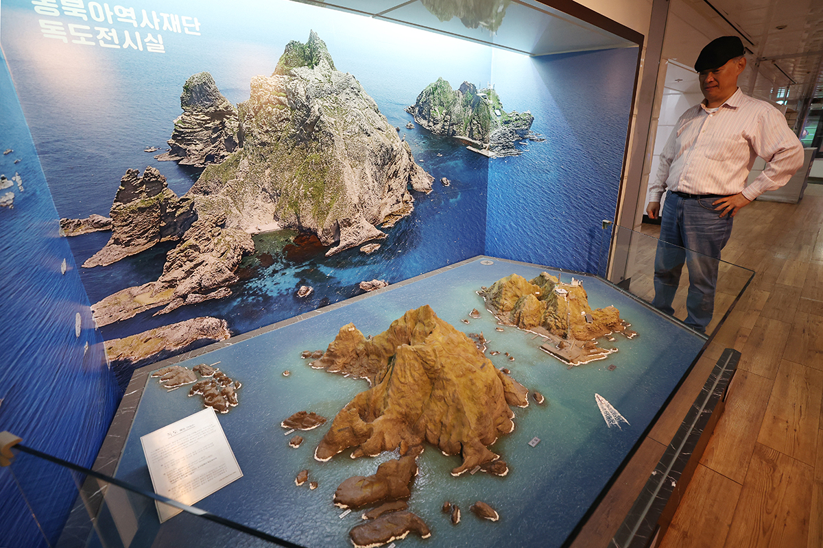 Un visiteur regarde une maquette des îlots Dokdo, à l’exposition permanente installée dans la station de métro de Gwanghwamun, à Séoul, à la veille de la journée dédié à la reconnaissance de ces îlots en tant que territoire coréen, le 24 octobre 2025.
