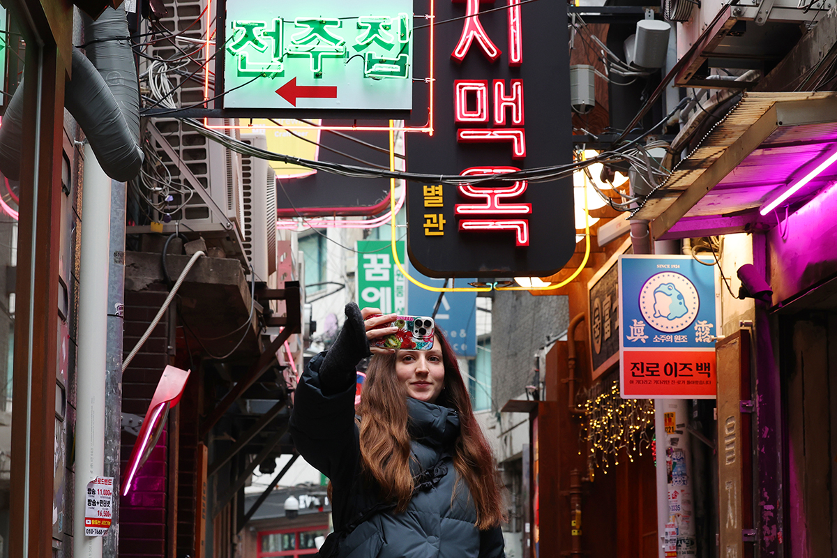 Une touriste étrangère photographie les ruelles d’Euljiro, à Séoul, le 10 décembre 2025. © Lee Jeong Woo / Korea.net