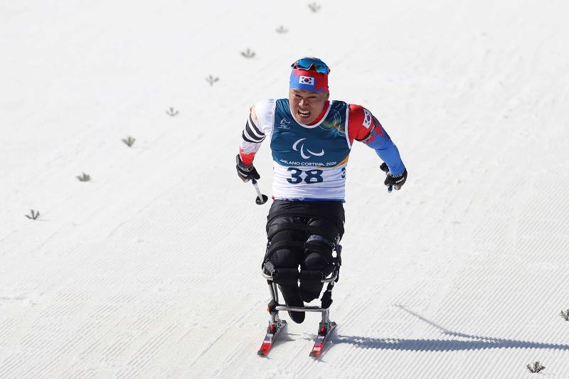Sin Euihyun, médaillé d’argent en para ski de fond à PyeongChang 2018, est en pleine descente sur la piste de Tesero lors du sprint assis en para biathlon, le 7 mars 2026. © Comité paralympique coréen