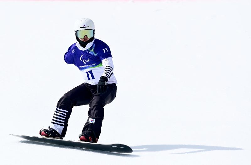 Lee Chungmin est en action lors du banked slalom SB-UL, une épreuve de snowboard réservée aux athlètes présentant une limitation modérée des avant-bras, à Cortina, le 13 mars 2026. © Comité paralympique coréen
