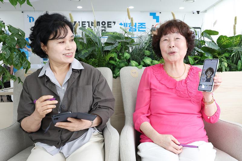 Kim Eun-seok (à droite) montre un dessin de sa création généré grâce à l’IA aux côtés de Lee Eun-jeong, au centre d’apprentissage numérique du quartier de Gangseo, à Séoul, le 28 mai 2026. © Lee Jeong Woo / Korea.net